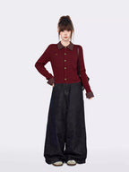 Full body shot of a woman in a burgundy cable knit cropped cardigan and wide-leg jeans.