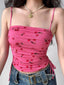 Close-up of a pink mesh crop top with a cherry print, featuring spaghetti straps and ruched detailing.