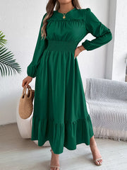 woman wearing a long green dress with long sleeves and a smocked waist