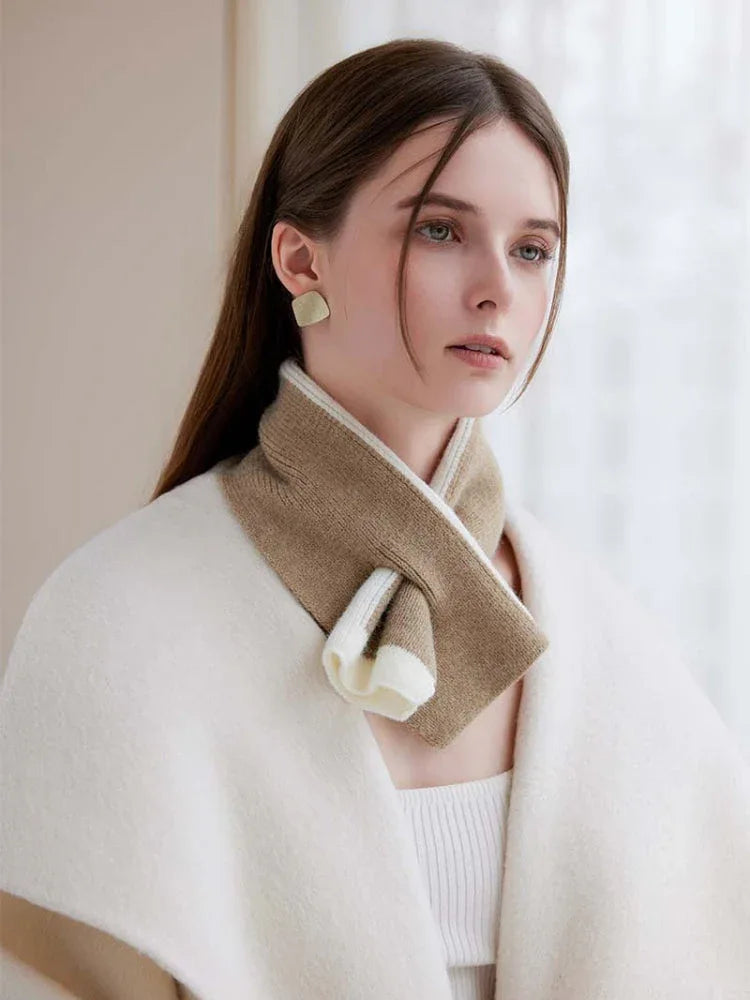 Woman wearing a cream colored cape and a tan and white striped scarf