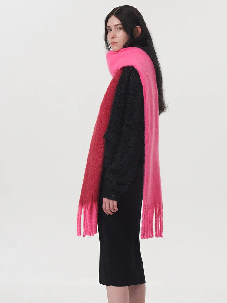 Side view of a woman wearing a black sweater and a two-toned pink and red scarf.