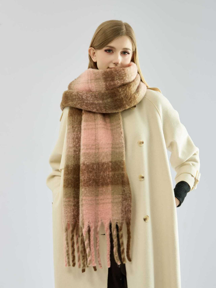 Woman wearing a cream-colored coat and a large plaid scarf in shades of pink and brown.