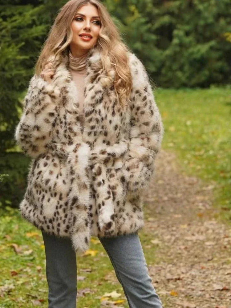 Woman wearing a spotted faux fur coat, grey jeans, and a turtleneck, posing outdoors in a wooded area.