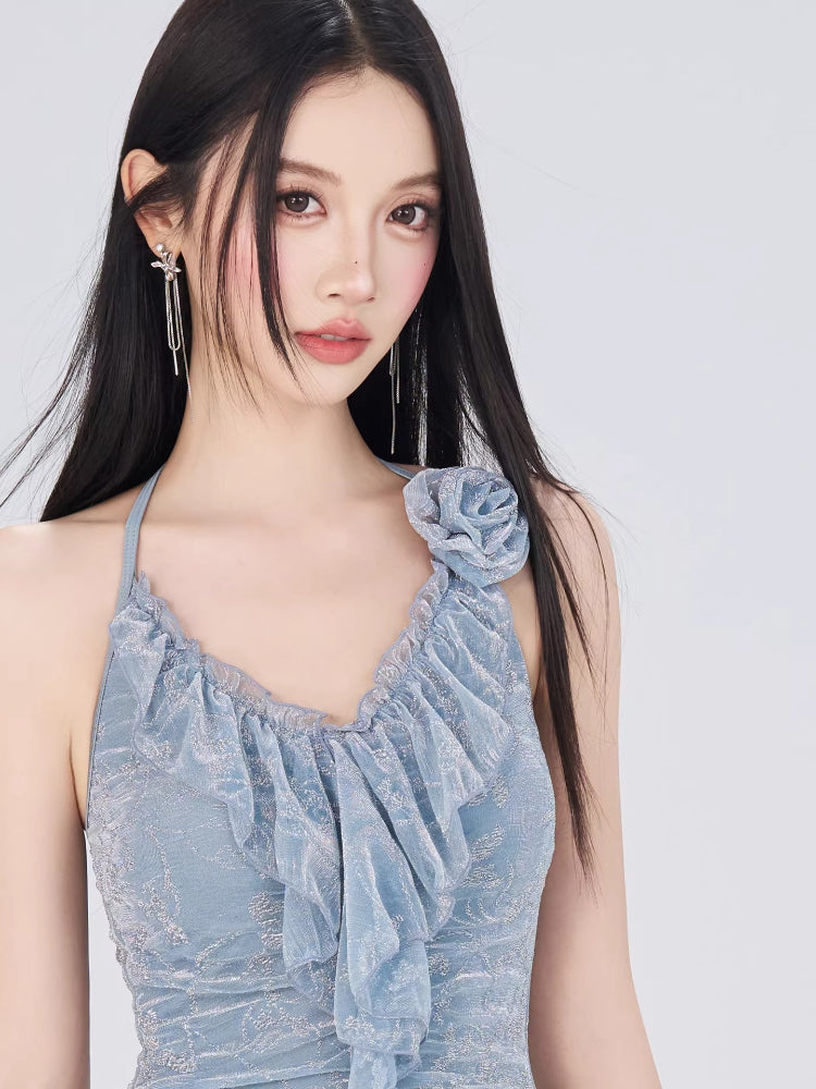 Close-up of the ruffled neckline and floral embellishment on the light blue halter dress.