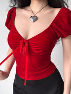A person wearing a red velvet tie-front top, showing the tie detail.