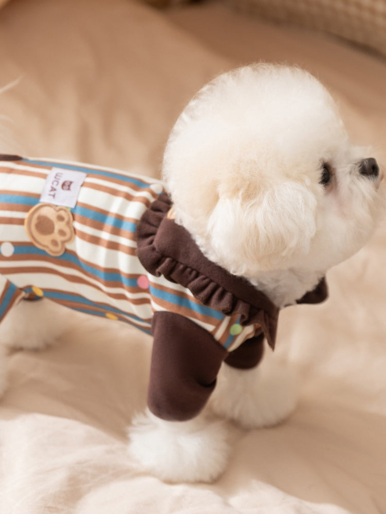 Profile view of a white dog wearing a brown and tan striped jumpsuit.