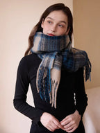 Model wearing a blue and tan plaid scarf with fringe