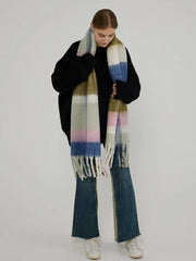Woman in a black sweater and jeans, holding a large plaid scarf with green, pink, blue, and white blocks.