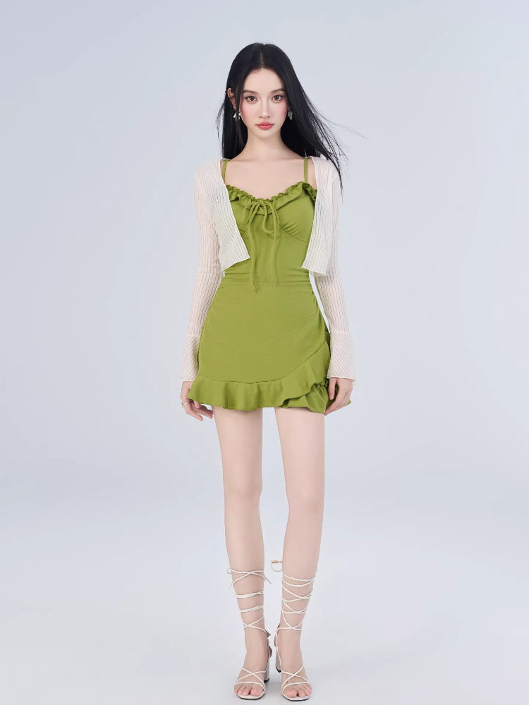 Full body shot of a woman in a green ruffled dress and white cardigan