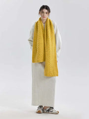 Full body shot of a woman wearing a long yellow cable knit scarf and a gray dress