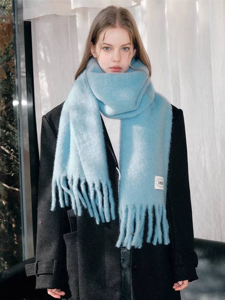 Woman wearing a light blue fluffy knit scarf draped around her neck and shoulders.