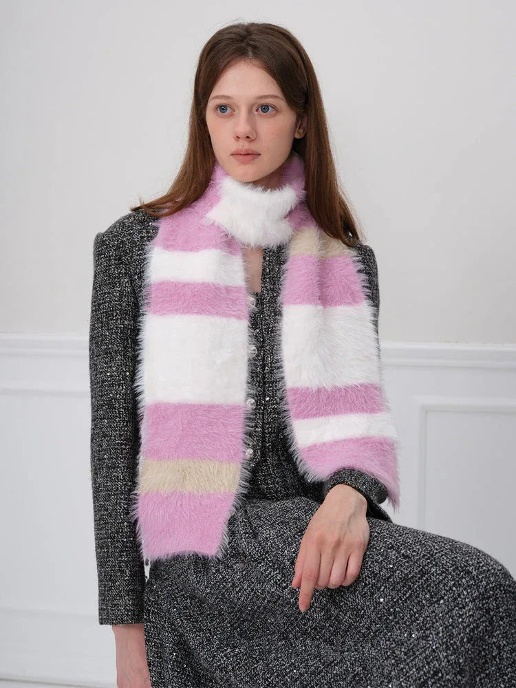 Close-up of a woman wearing a pink, white, and beige striped fuzzy scarf.