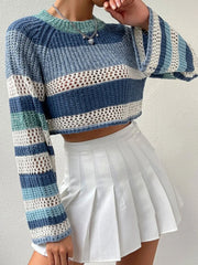 Woman adjusting her blue and white striped crochet knit cropped sweater with bell sleeves while wearing a white pleated mini skirt.
