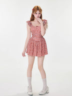 Full body shot of a woman in a red and white gingham dress, white lace socks, and white platform shoes.