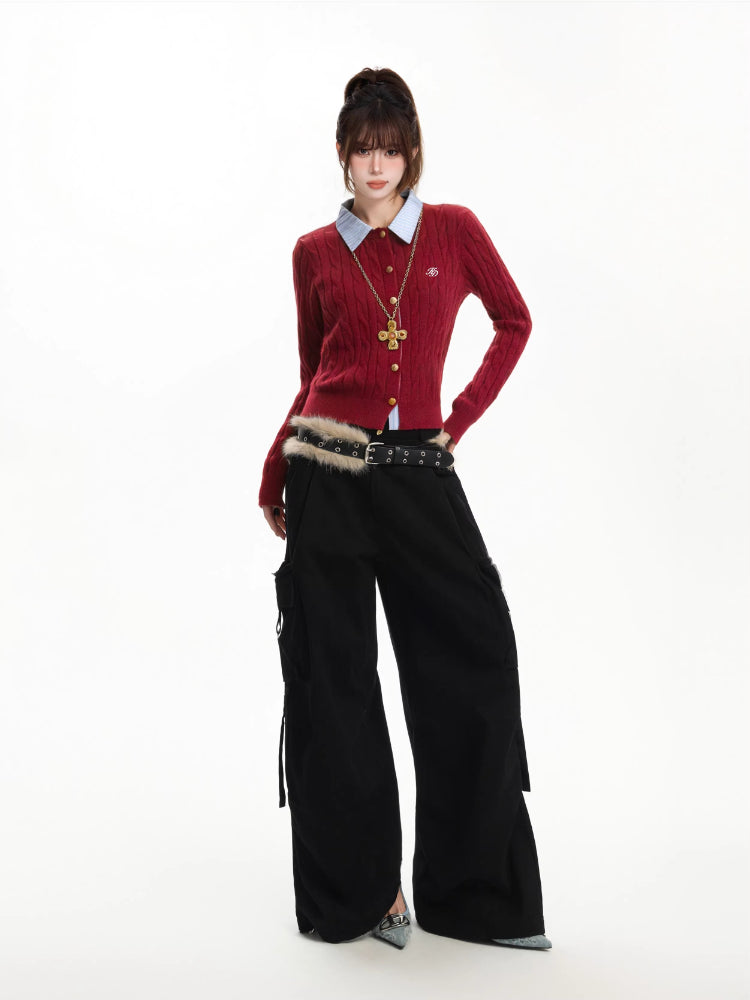 Woman posing in a red cable knit cardigan, light blue collared shirt, black cargo pants with a furry belt, and high heels.