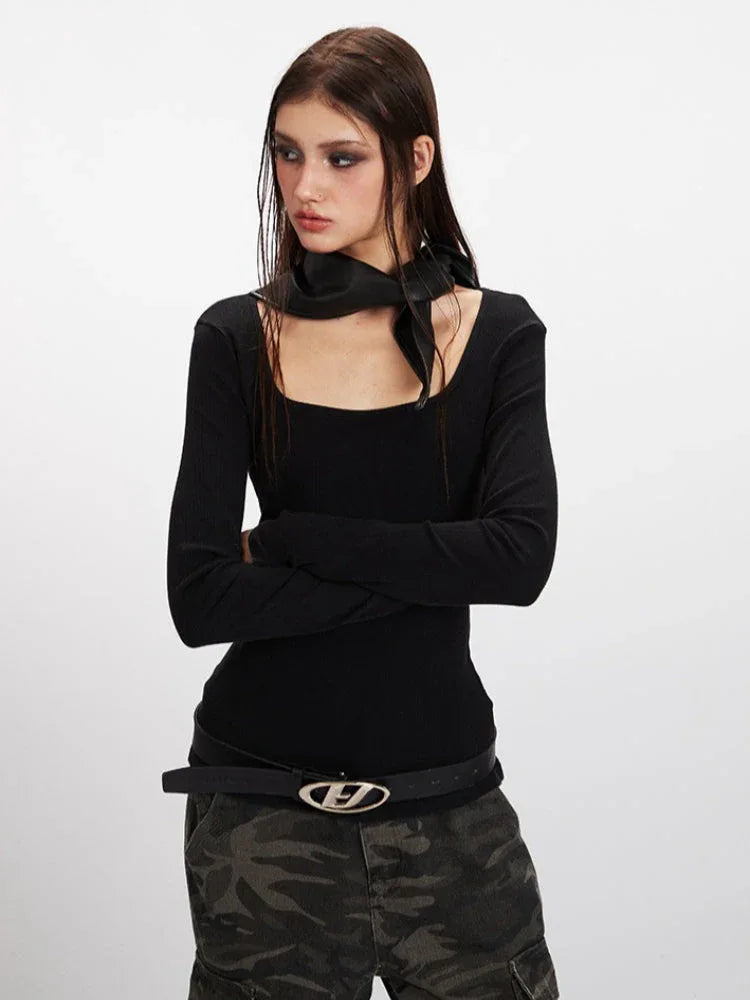 Woman in a black long-sleeve top and camouflage cargo pants, with arms crossed.