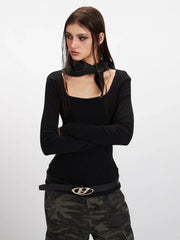 Woman in a black long-sleeve top and camouflage cargo pants, with arms crossed.