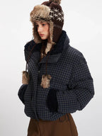 Side view of a woman in a plaid puffer jacket and trapper hat, looking to the side.