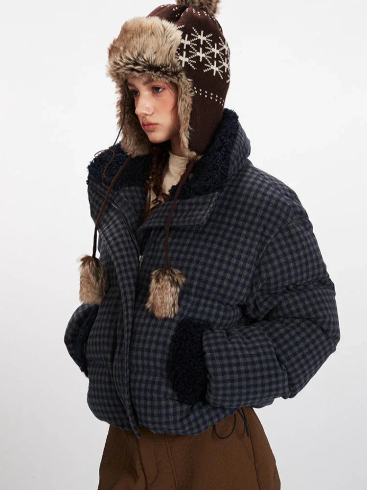 Side view of a woman in a plaid puffer jacket and trapper hat, looking to the side.
