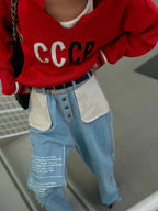Close-up of a red CCCP knit sweater worn with light blue jeans and a white tank top.