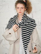 Model wearing a beige coat and black and white striped scarf