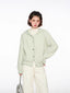 Woman wearing a light green hooded cardigan with white pants and a silver bag, front view