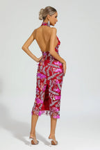 Rear view of a woman in a red sequined halter midi dress with floral appliques and an open back.