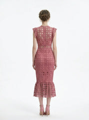 Woman wearing a pink lace dress with ruffled cap sleeves and a mermaid hemline, back view.