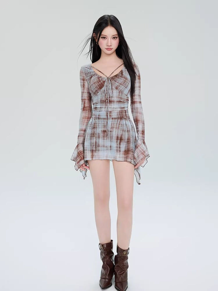 Full-length view of a woman in a plaid mesh mini dress and brown boots.