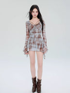 Full-length view of a woman in a plaid mesh mini dress and brown boots.