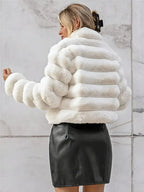 Back view of a woman wearing a white faux fur cropped jacket and a black skirt.