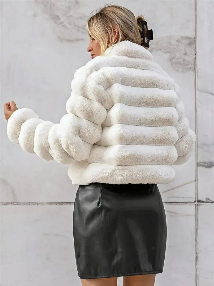 Back view of a woman wearing a white faux fur cropped jacket and a black skirt.