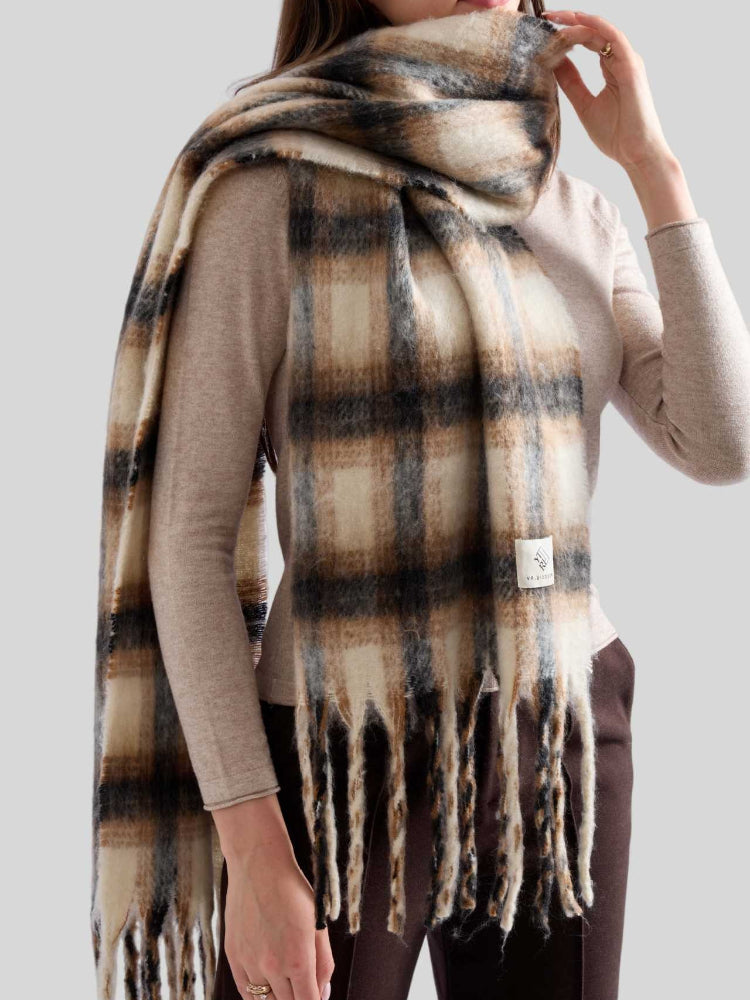 Front view of a woman wearing a large plaid scarf wrapped around her neck, with the fringe hanging down.