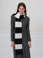 Woman wearing a black and white checkered faux fur scarf over a grey tweed jacket and skirt