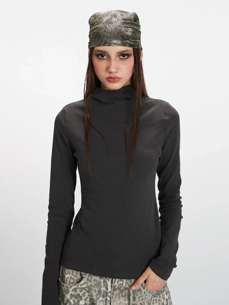Front view of a woman's upper body wearing a grey turtleneck top and leopard print pants.
