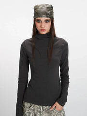 Front view of a woman's upper body wearing a grey turtleneck top and leopard print pants.