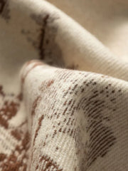 Close-up of the woven texture of a cream fabric with a brown pattern