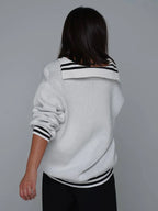 Back view of a woman wearing a white CCCP knit sweater with a sailor-style collar and black stripes.