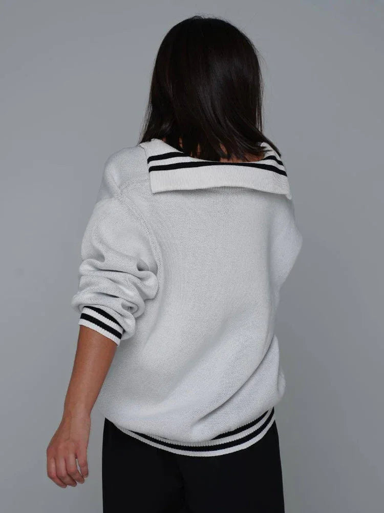 Back view of a woman wearing a white CCCP knit sweater with a sailor-style collar and black stripes.
