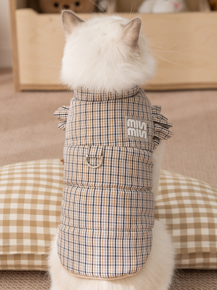 Rear view of a white cat wearing a brown plaid vest with ruffled sleeves.