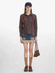 Full-body front view of a woman wearing a plaid button-down shirt, denim mini skirt with faux fur trim, and a tie.