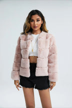 Woman wearing a pink faux fur cropped jacket, hands clasped in front.
