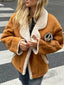 Woman wearing a brown suede jacket with white shearling trim and collar, standing on a crosswalk.