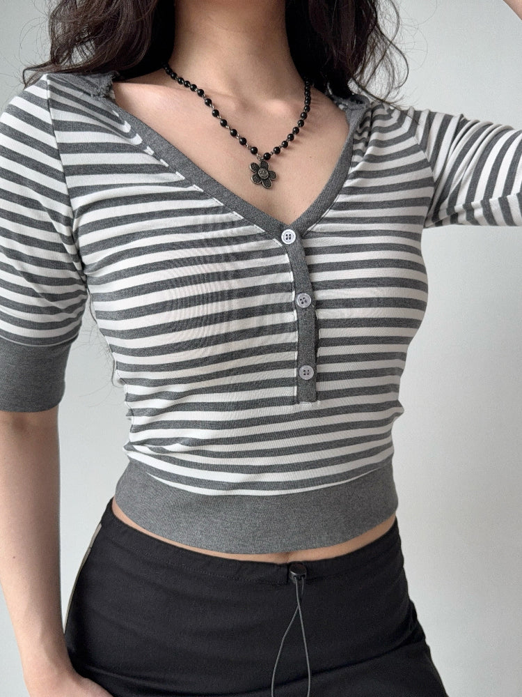 Woman in a grey and white striped cropped top with a v-neck and button front, showing the side view.