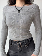 Close-up of a grey cable knit cropped sweater with an off-the-shoulder neckline and button details.