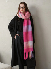 A woman wearing a dark coat and a long, brightly colored plaid scarf.