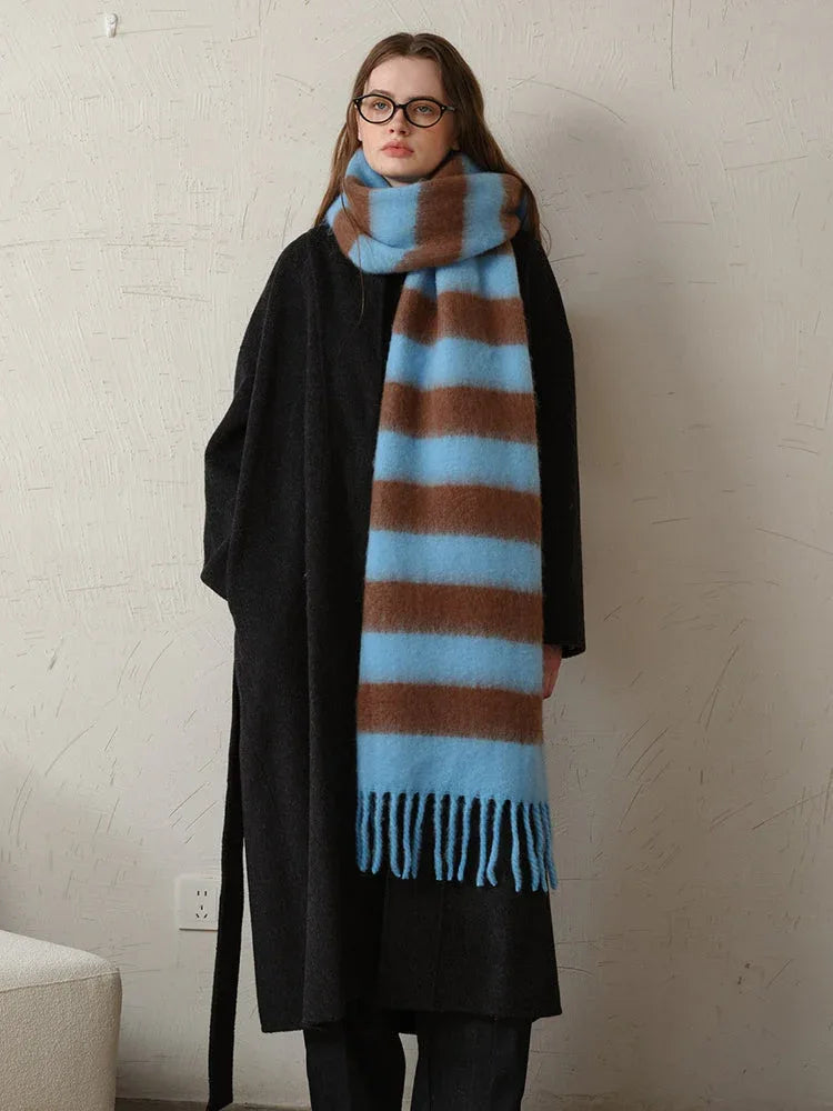Woman wearing a black coat and a blue and brown striped scarf with fringe detail