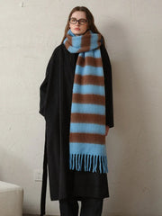 Woman wearing a black coat and a blue and brown striped scarf with fringe detail