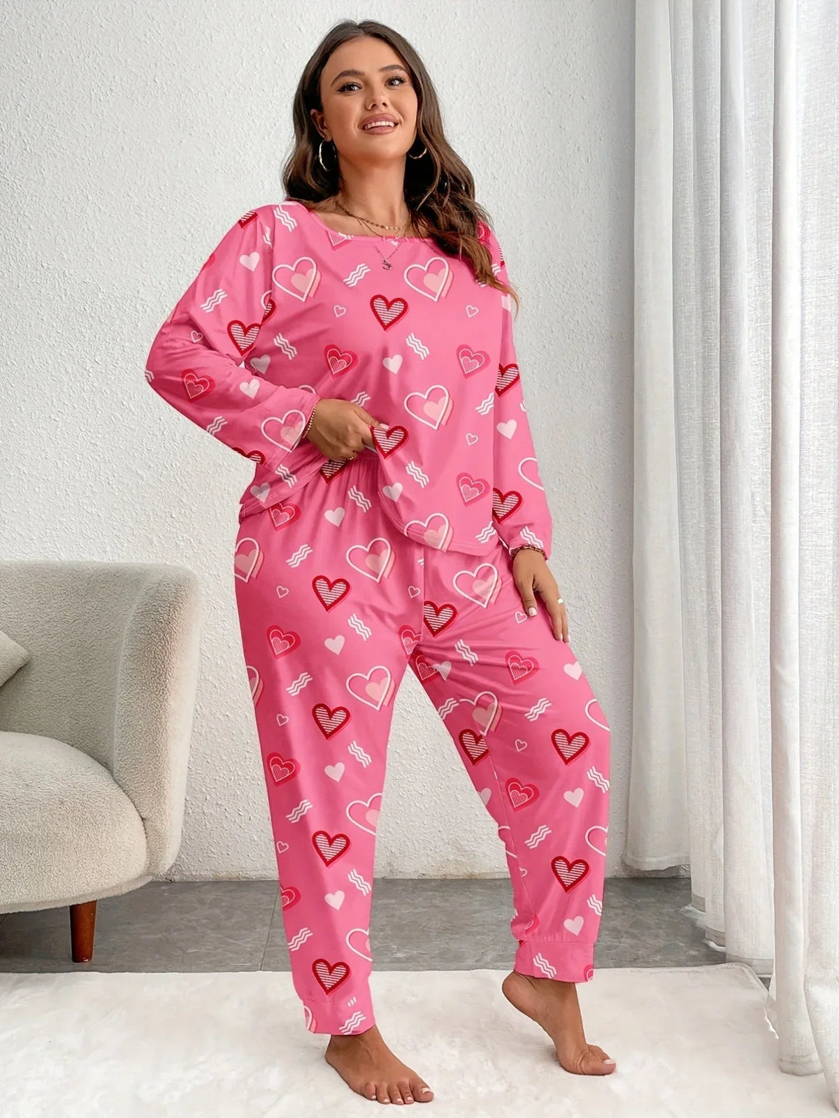 Woman wearing pink heart-print pajamas, standing and adjusting her waistband.