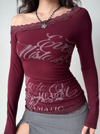 Model wearing a burgundy off-the-shoulder long-sleeve top with lace trim and a graphic print.